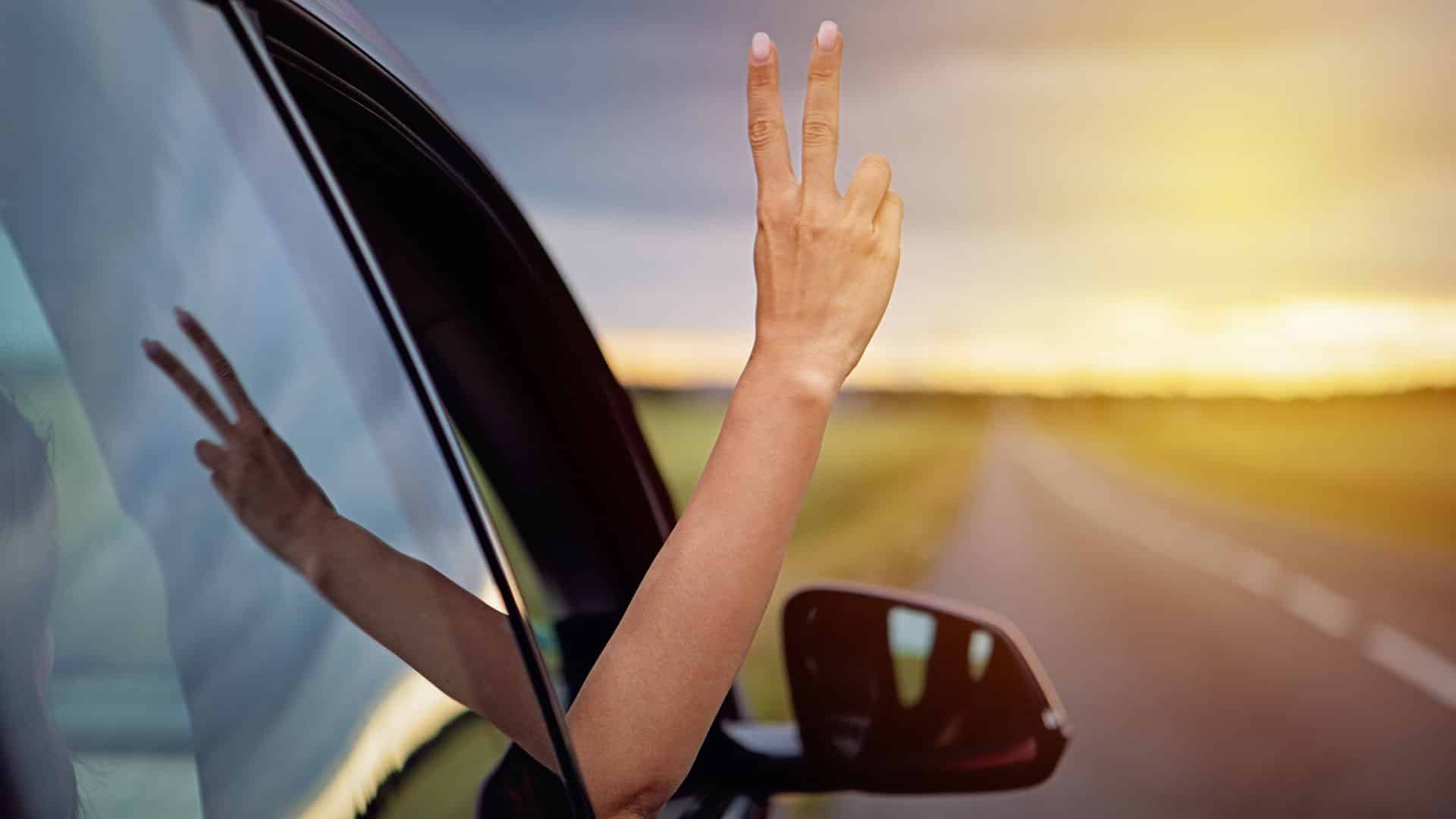 Woman showing a peace sign out a moving EV